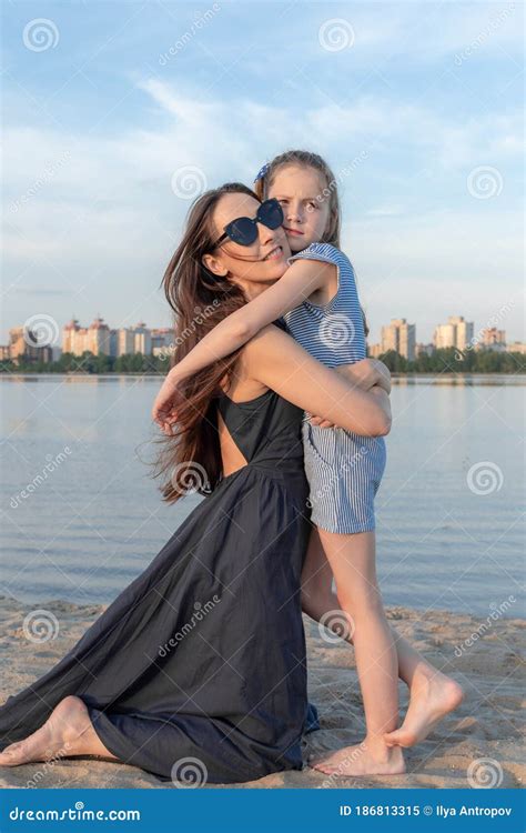 Mother Is Kneeling In Front Of Her Daughter On The Lake Shore They Hug