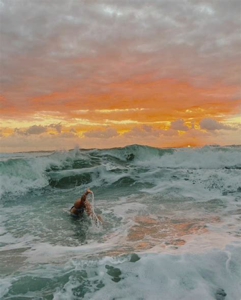 A Person Swimming In The Ocean At Sunset With Waves Coming Up Behind