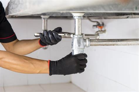 Technician Plumber Using A Wrench To Repair A Water Pipe Under The Sink