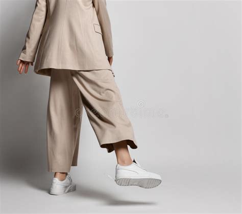 Legs Of Woman In Beige Business Smart Casual Pantsuit Sneakers Walking Over Light Stylish