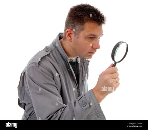 Man With Raincoat Is Looking With Magnifying Glass Over White