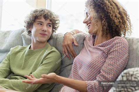Happy Mother And Son Talking On Couch In Living Room Front View