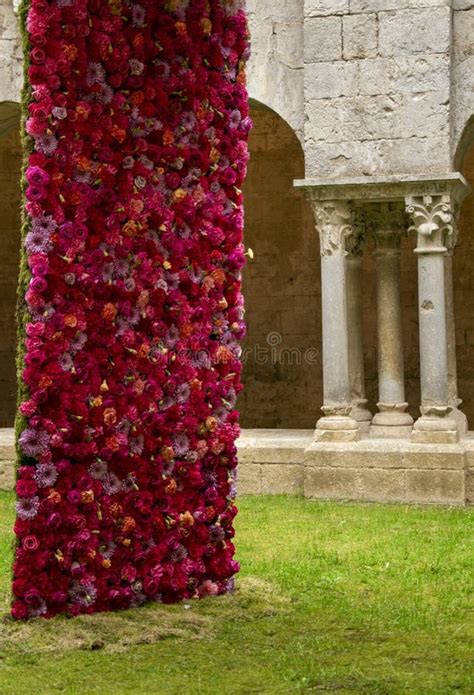 Una Columna De Flores Delante De Una Pared De Piedra Foto De Archivo