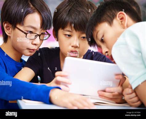 Three Asian Primary School Student Playing Video Game Using Tablet