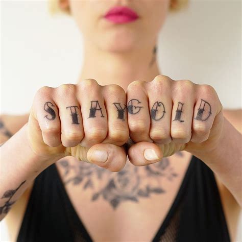 A Woman With Tattoos On Her Hands Holding Up The Word Stay Gold