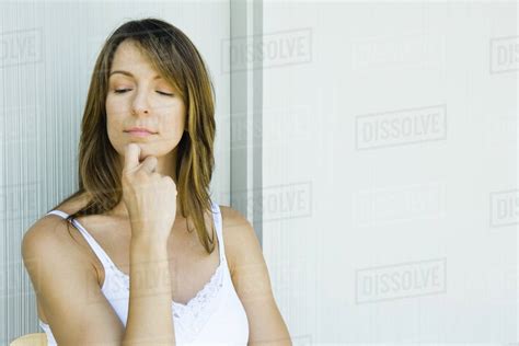 Woman With Hand Under Chin Looking Down Eyes Half Opened Stock