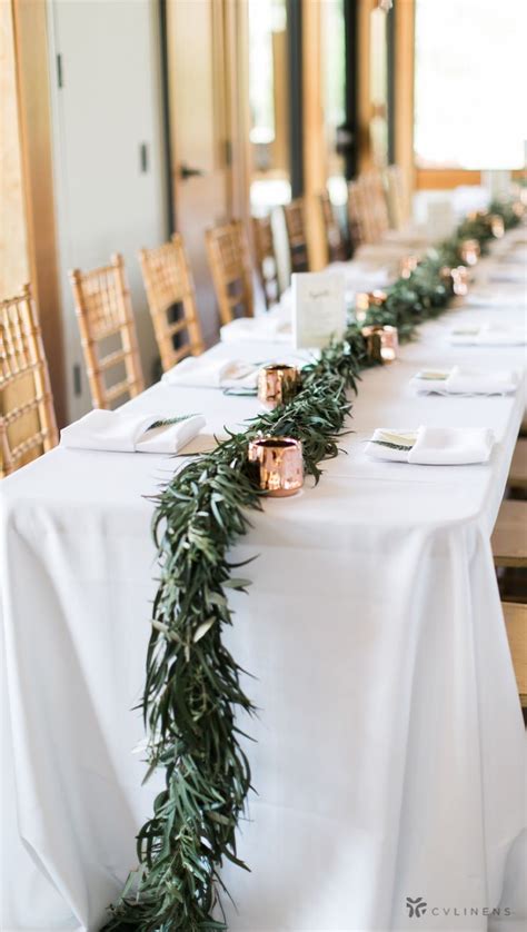 A Long Table With Candles And Greenery On It