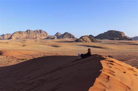 Arab Man In Wadi Rum Desert Sitting Over A Dune In Arabian Desert And