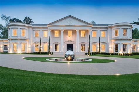 A Large White House With Lots Of Windows And Lights On Its Front Lawn