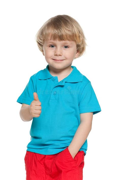 Little Blond Boy In Blue Shirt Holds His Thumb Up Stock Photo Image
