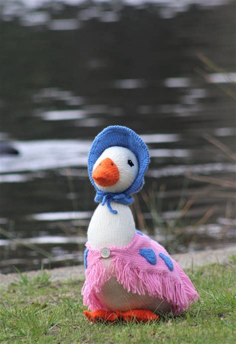 A Stuffed Duck Wearing A Blue Hat And Pink Dress Sitting On The Grass
