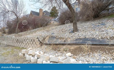 Panorama Stone Blocks Of Collapsed Retaining Wall Holding The Soil Of A Slope With Houses Stock