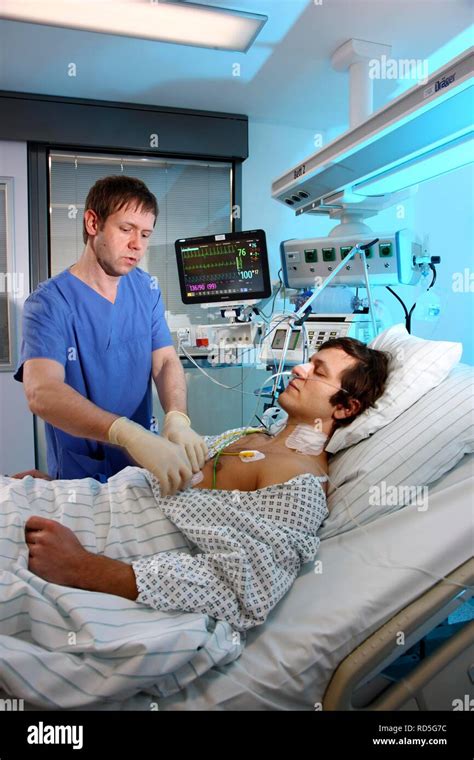 Male Intensive Care Nurse Looking After A Patient Lying In A Special
