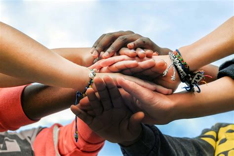 Multiracial teen friends joining hands together in cooperation ...