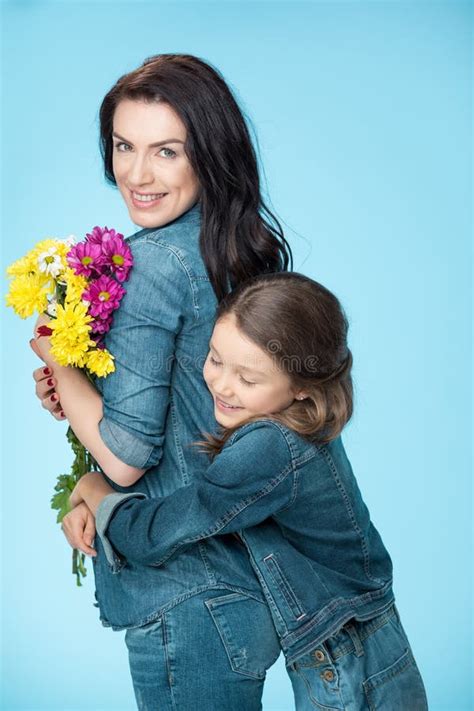 Madre E Hija Que Abrazan Y Que Sostienen Las Flores En Estudio En Día
