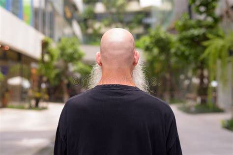 Rear View Of Mature Bald Bearded Man Looking At Nature In The City