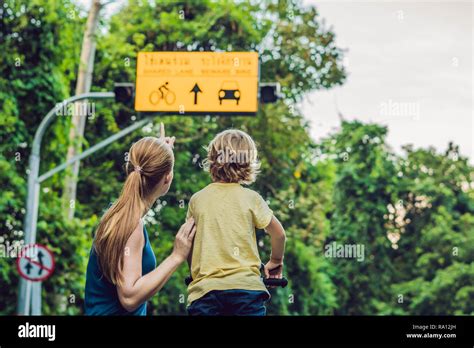 Mom shows his son a plate of shared lane and beware bike warning sign