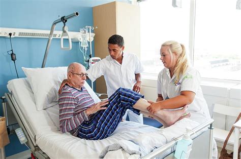 nurses helping senior man into hospital bed photograph by arno massee science photo library pixels