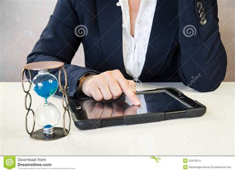 Hand Hourglass And Tablettyping Message Into Mobile Stock Photo