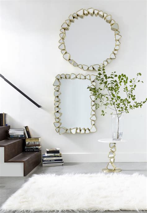 Pebble Shaped Mirrors Encased In A Brushed Brass Finish Are Stacked