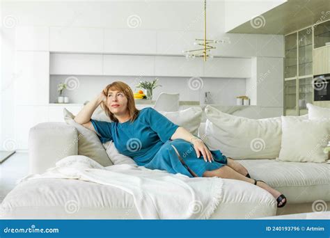 Attractive Mature Woman Relaxing On The Sofa At Home Stock Photo