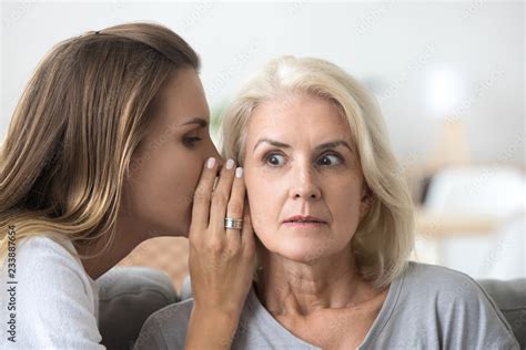 Foto Stock Shocked Older Woman Listening To Young Female Whispering In