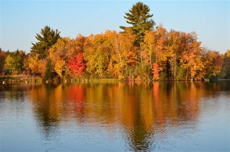 Lush Fall Colored Trees Reflection In Blue Lake Water Stock Photo