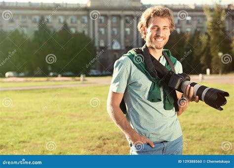 Handsome Male Photographer Holding Professional Camera On Street Stock