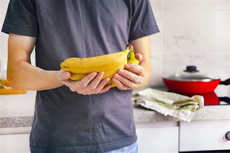 Man Standing In Kitchen And Holding Bananas In His Hands Stock Image