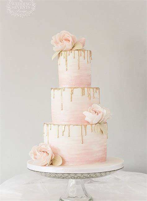 a three tiered cake with dripping icing and pink flowers on the top layer