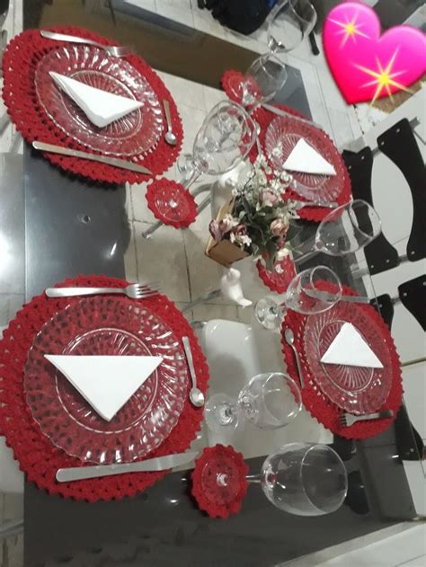 The Table Is Set With Red Glass Plates And Place Settings For Two