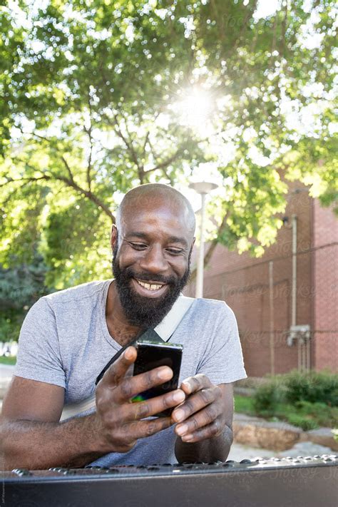 Man Reading Text Message In Park By Stocksy Contributor Jeff