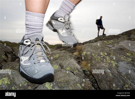 Close Up Of Hikers Feet Crossing Rocky Outcrop With Silhouetted Hiker