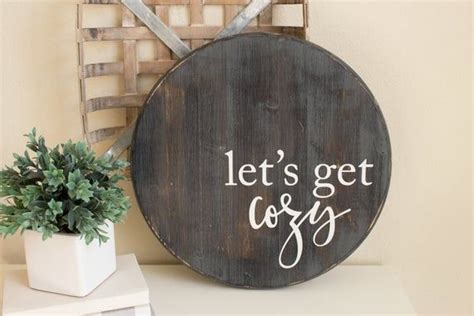 A Wooden Sign That Says Lets Get Cozy Next To A Potted Plant
