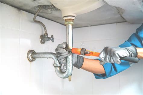 Technician Plumber Using A Wrench To Repair A Water Pipe Under The Sink