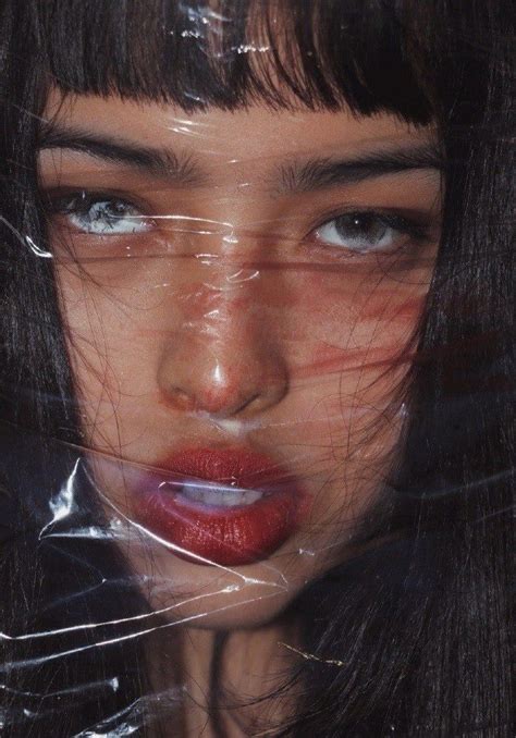 a woman with long black hair and blue eyes is wrapped up in plastic wrap to cover her face