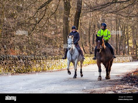 Two Horse Riders Riding Horses Hacking Along A Quiet Country Peak