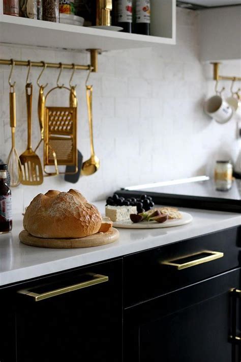 Marble Effect Tiles And Countertop With Black Kitchen Cabinets And Gold