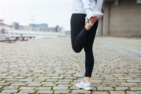 Fit young woman stretching her leg before a run Stretches Before