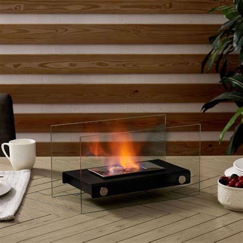It is a tabletop fireplace that has a stainless steel base and protective glass walls positioned on two sides of the burner. DanyaB Smokeless Bio-Ethanol Tabletop Fireplace | Wayfair