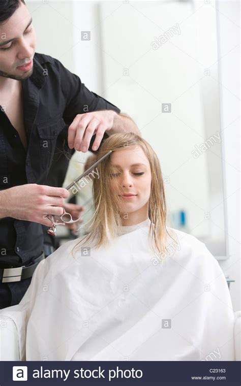 Man Cutting A Young Womans Hair In The Hairdressers Stock