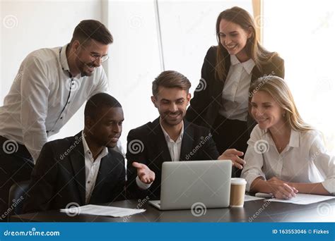 Smiling Diverse Employees Cooperating In Office Using Laptop Stock