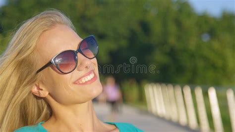 Close Up Attractive Blonde Woman Smiles For The Camera In The Green