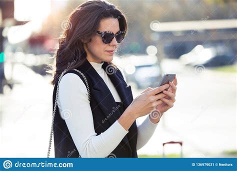 Pretty Young Woman Using Her Mobile Phone While Standing In The Street