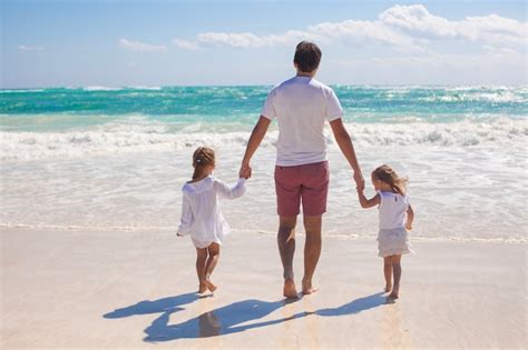Vista Trasera Del Padre Y Sus Dos Hijas Lindas Caminando En La Playa De