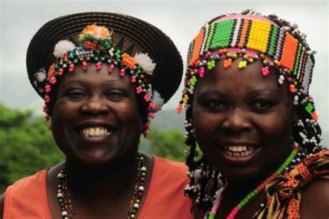 Two Women Wearing Headdresses And Smiling For The Camera