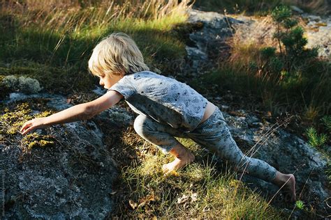 Boy Stretches While Climbing Barefoot On Rocks By Stocksy