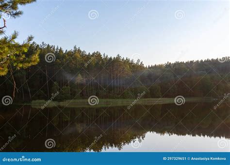 Lake Surrounded By Trees That Reflect In The Water Fog On The Surface