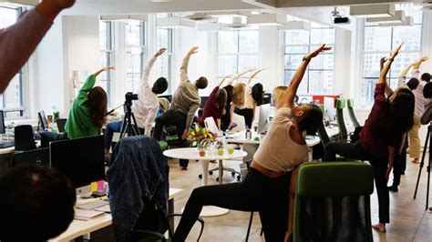 A Group Of People Doing Yoga Exercises In An Office Setting With Their