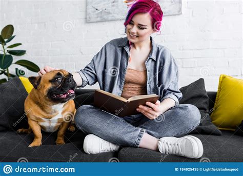 Girl With Colorful Hair Sitting On Sofa With Book And Petting Cute